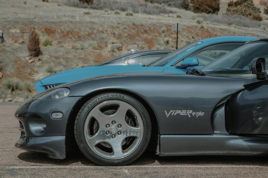 A detailed view of a Dodge Viper sports car parked outdoors at a car show against a natural background.