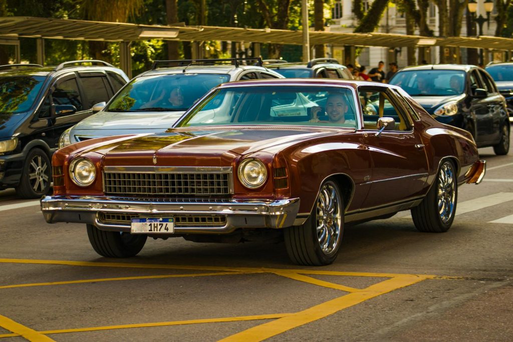 A classic Chevrolet Monte Carlo cruising through busy city streets with vintage charm.