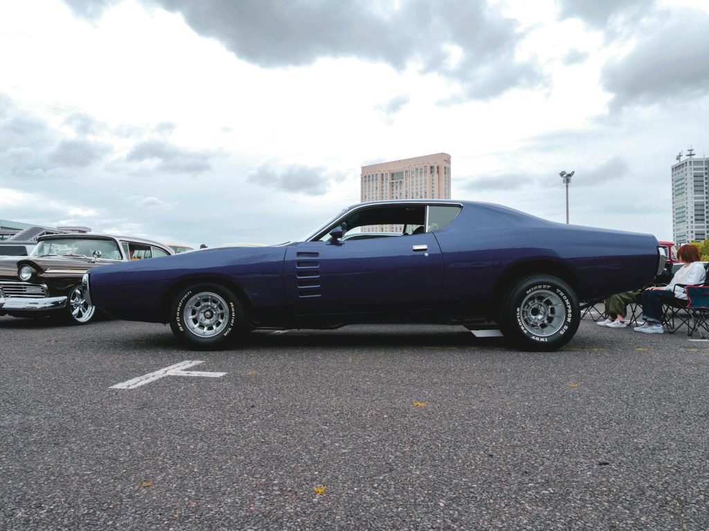 Classic muscle car parked outdoors with cityscape background. Ideal for automotive enthusiasts.