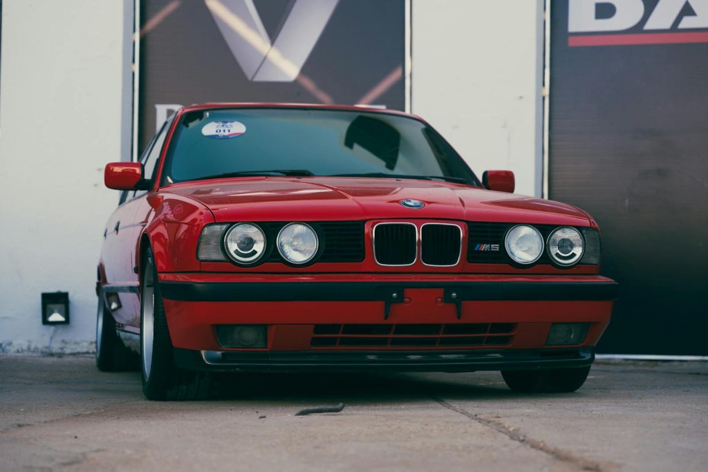 Front view of a vintage red BMW M5 E34 parked outdoors in Benghazi, Libya.