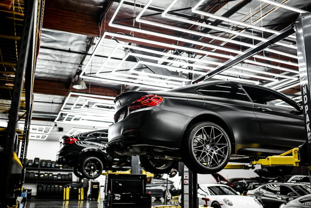 A modern car repair shop showcasing vehicles on lifts and a well-lit, organized interior.