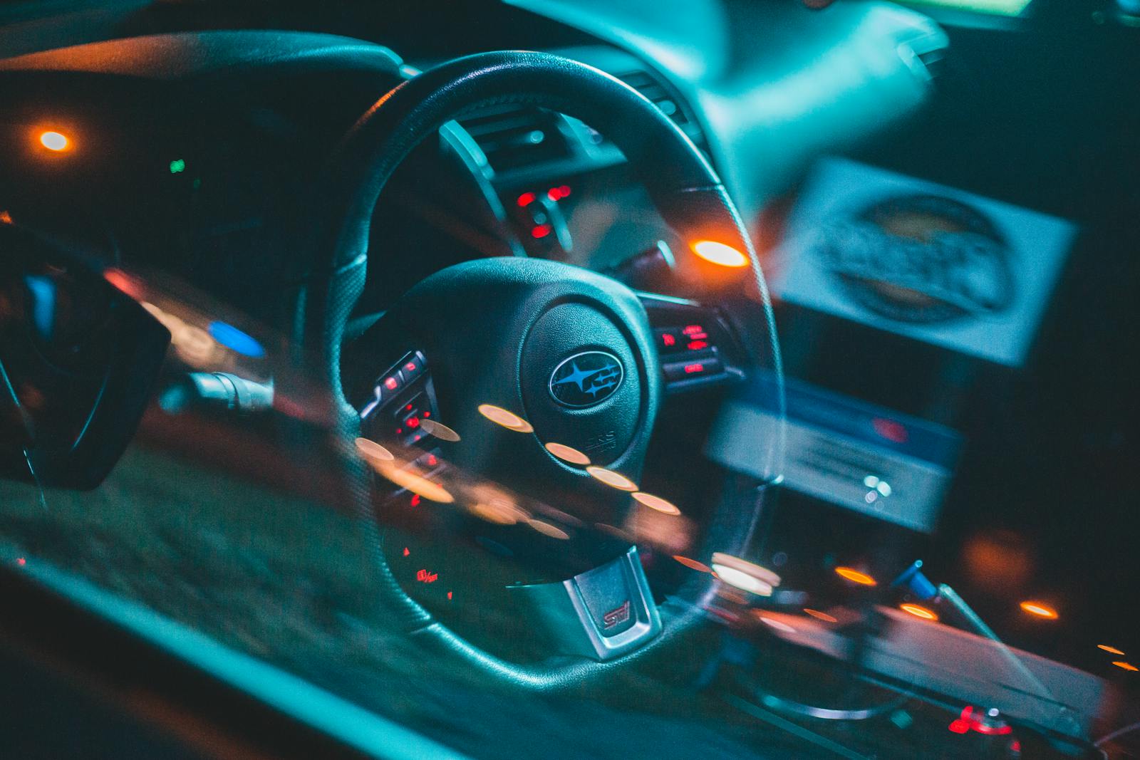 Dynamic close-up of a Subaru car interior showcasing steering wheel and dashboard with colorful lights.