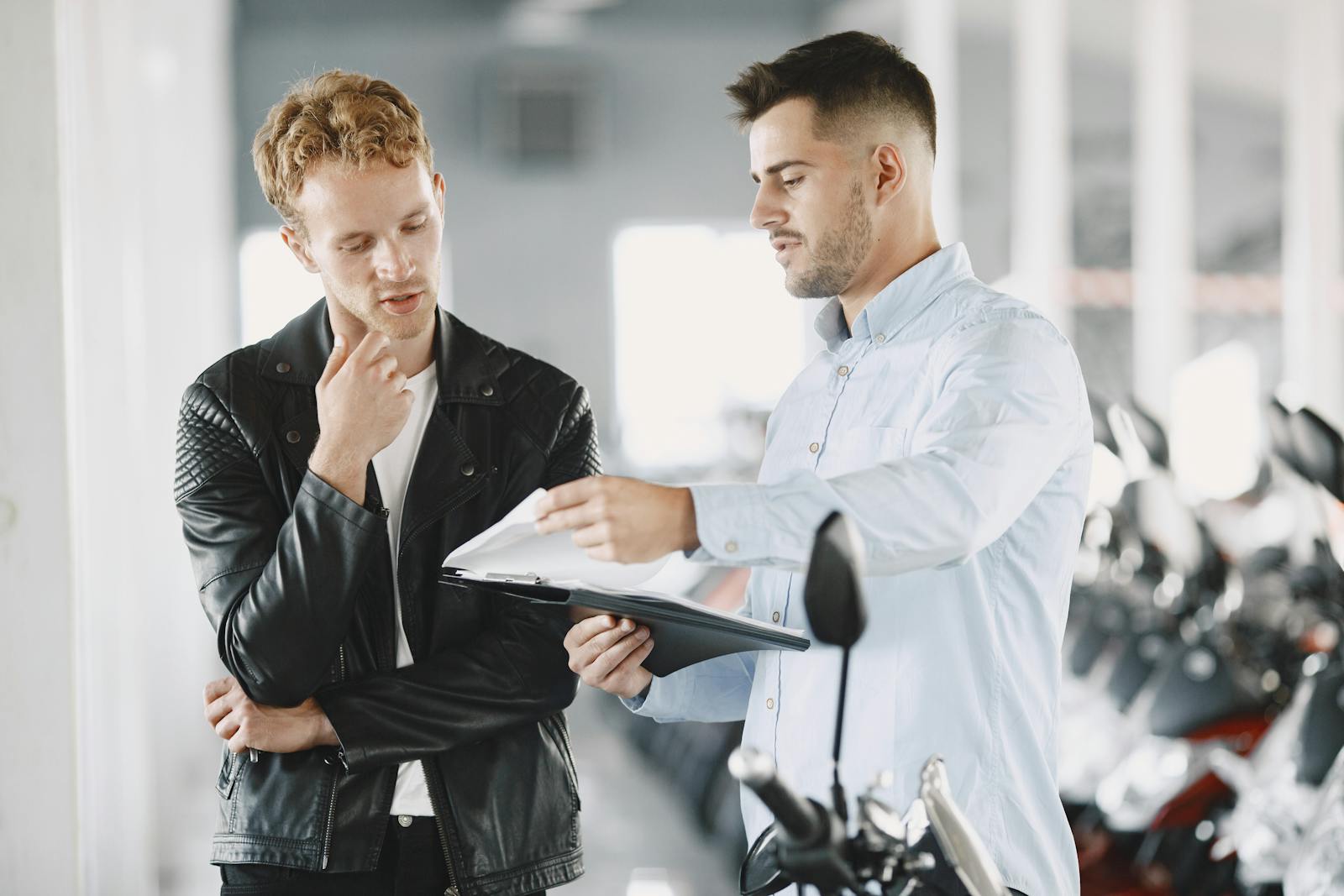 Two adults discussing purchasing options at a motorcycle dealership.