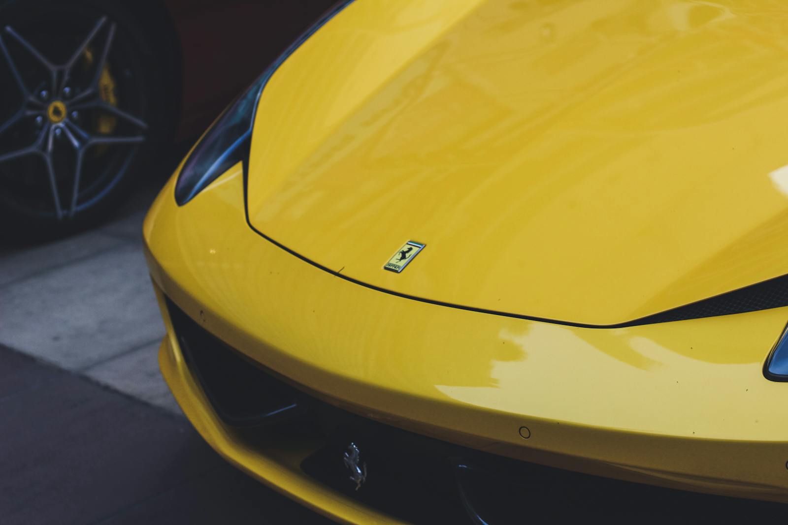 Close-up of a sleek yellow Ferrari sports car, showcasing luxury automotive design.