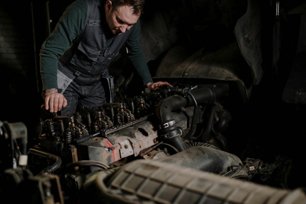 Mechanic focused on vehicle engine repair in an indoor workshop.