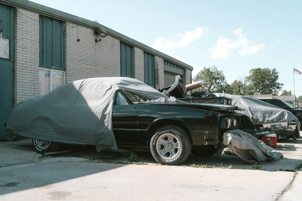 a car covered in a tarp parked in front of a building