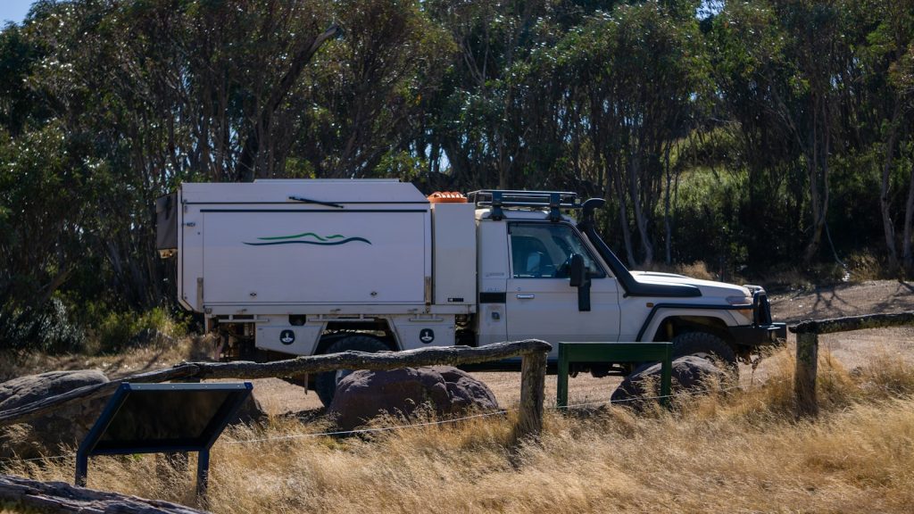 a white truck parked on top of a dry grass field