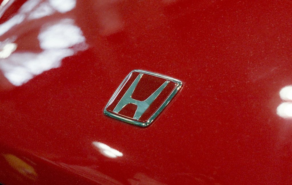 Close-up of a red honda car emblem.