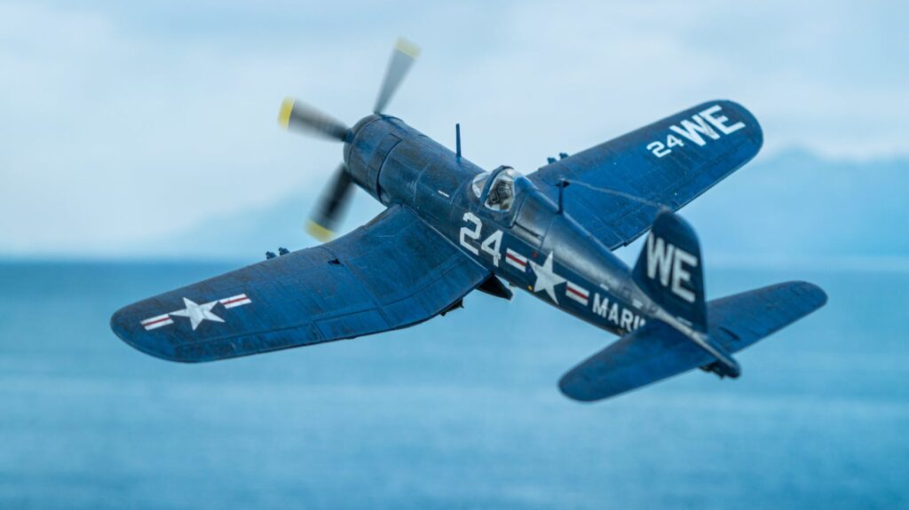 A detailed view of a Corsair fighter plane flying over the ocean, evoking WWII history.