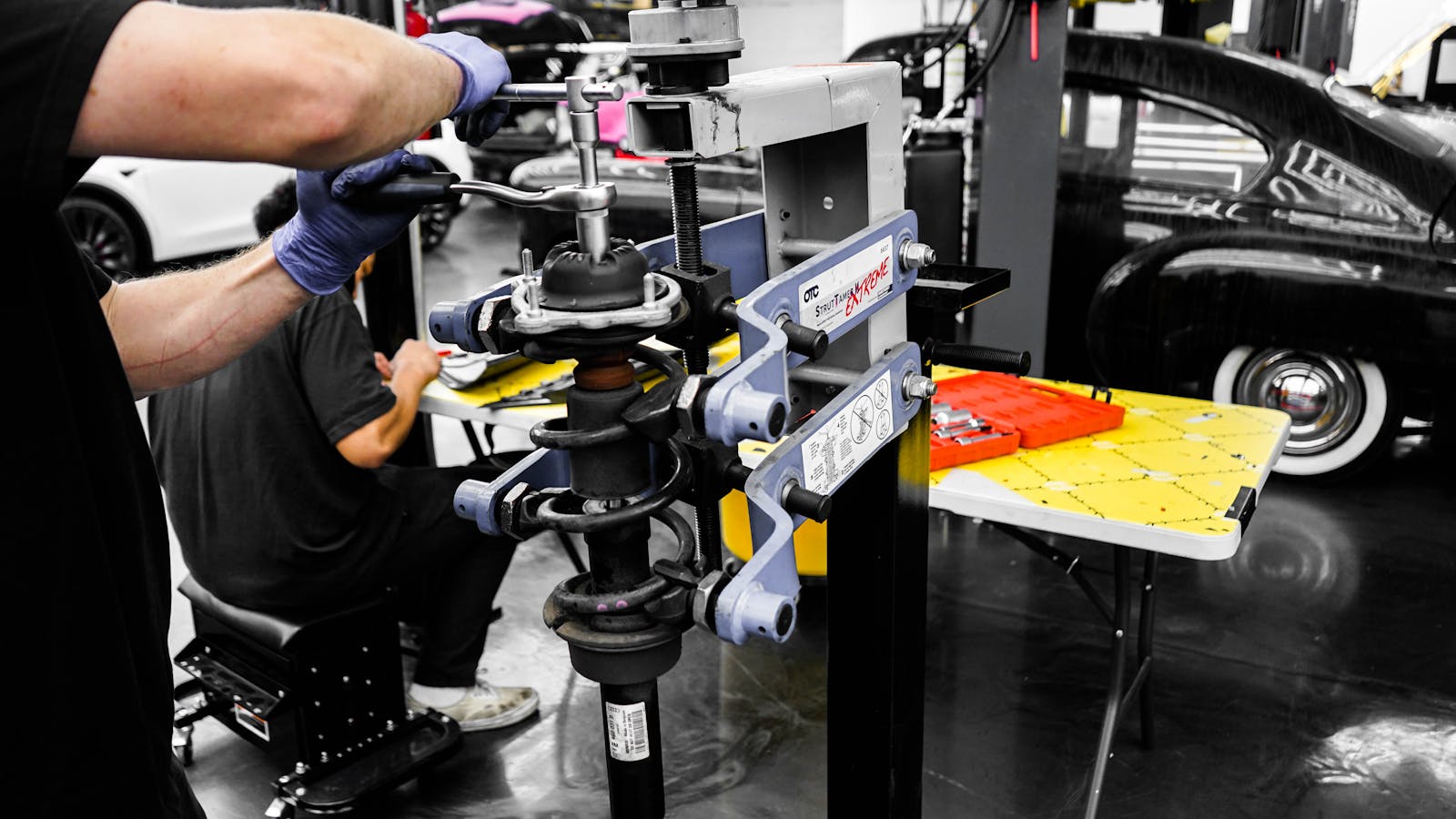 Mechanics using specialized equipment to repair vehicles in an automotive workshop.