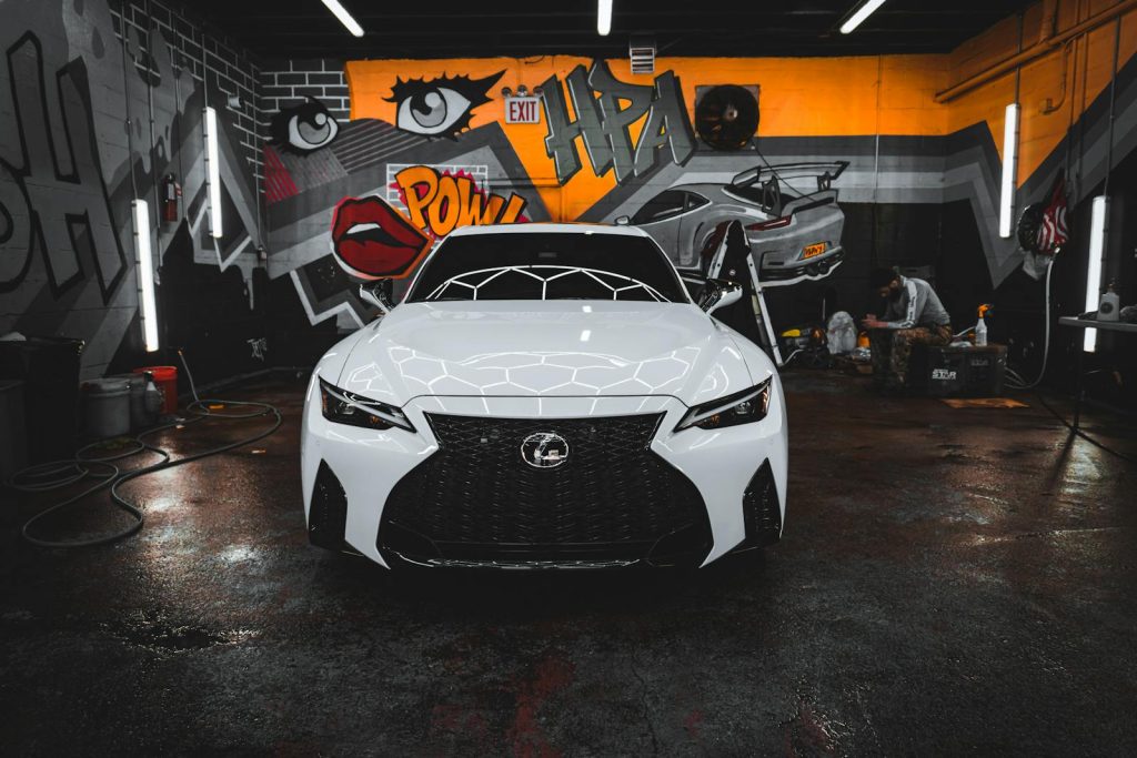 Front view of a luxury white Lexus car in a graffiti-adorned garage in New York City.