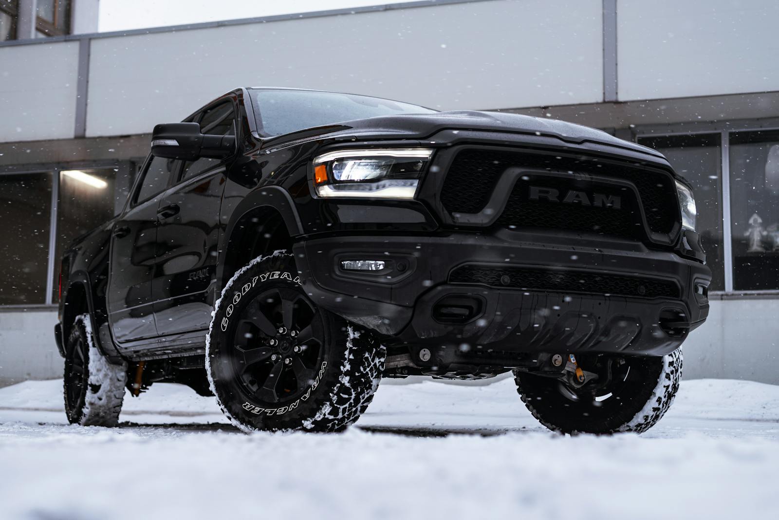 Black pickup truck parked on a snowy city street, showcasing rugged design and winter functionality.