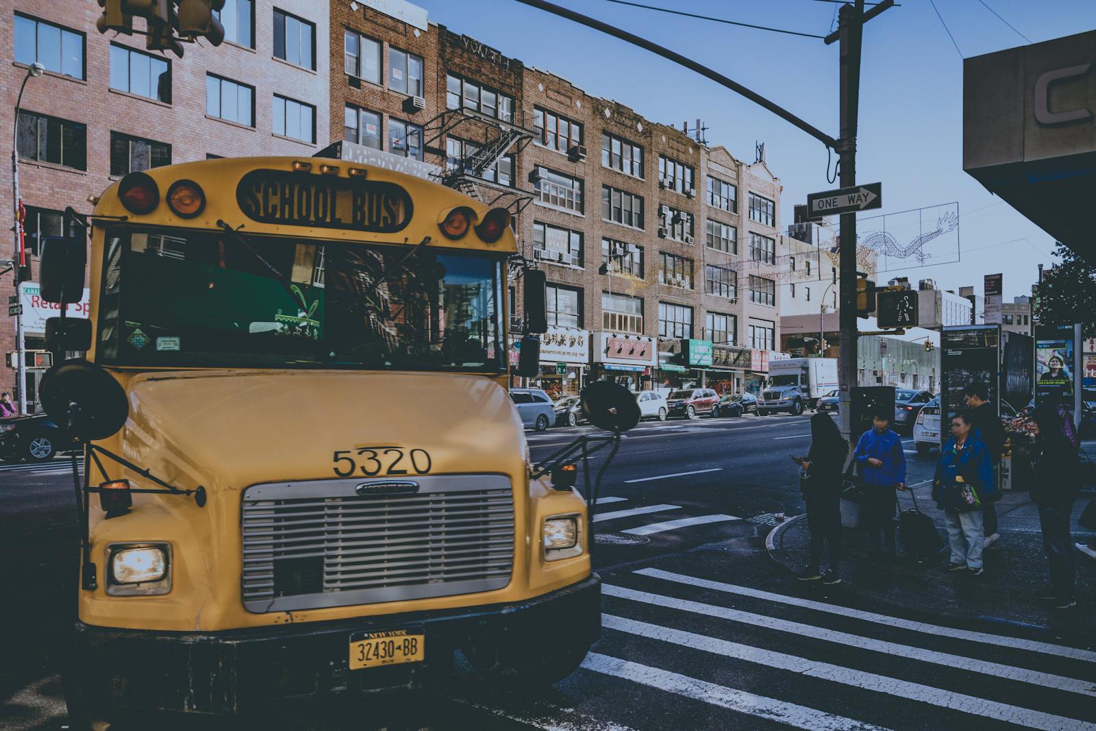Yellow school bus on a bustling city street with pedestrians in New York.