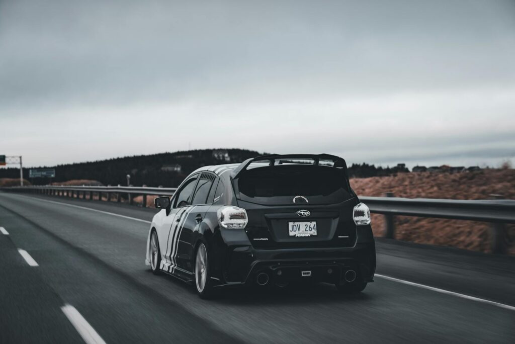 A sleek Subaru Impreza speeding down an empty highway under a cloudy sky, epitomizing freedom and adventure.