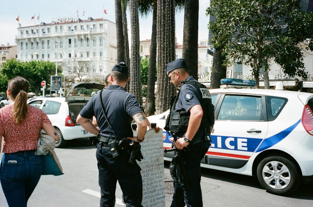 Police officers and a civilian interact near a police car on a busy city street.