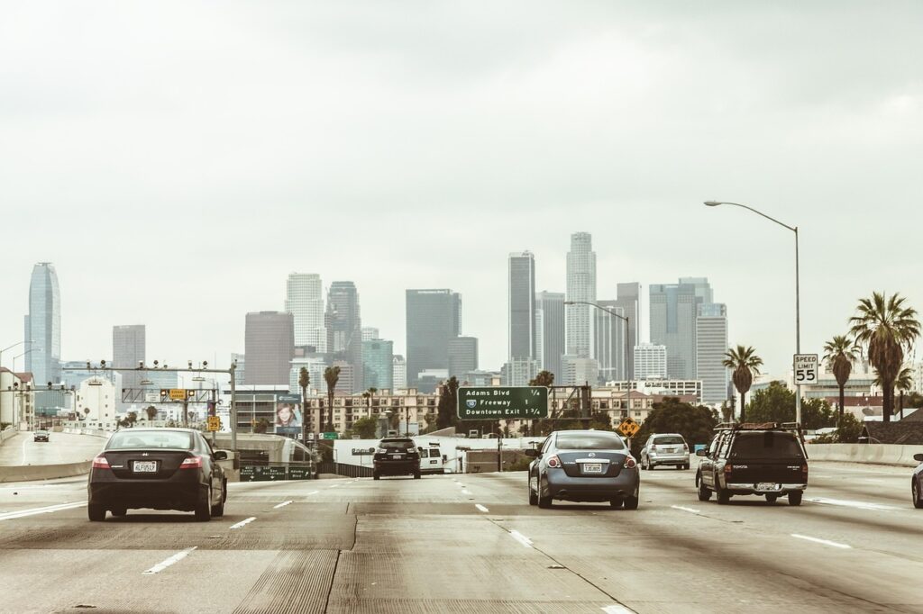 highway, cars, traffic, vehicles, towers, buildings, skyscrapers, los angeles, downtown, center, freeway, office center, city, megalopolis, business centre, architecture, office, high-rise, multistory building, motion, road, asphalt, street, transport, sky, nature, panorama