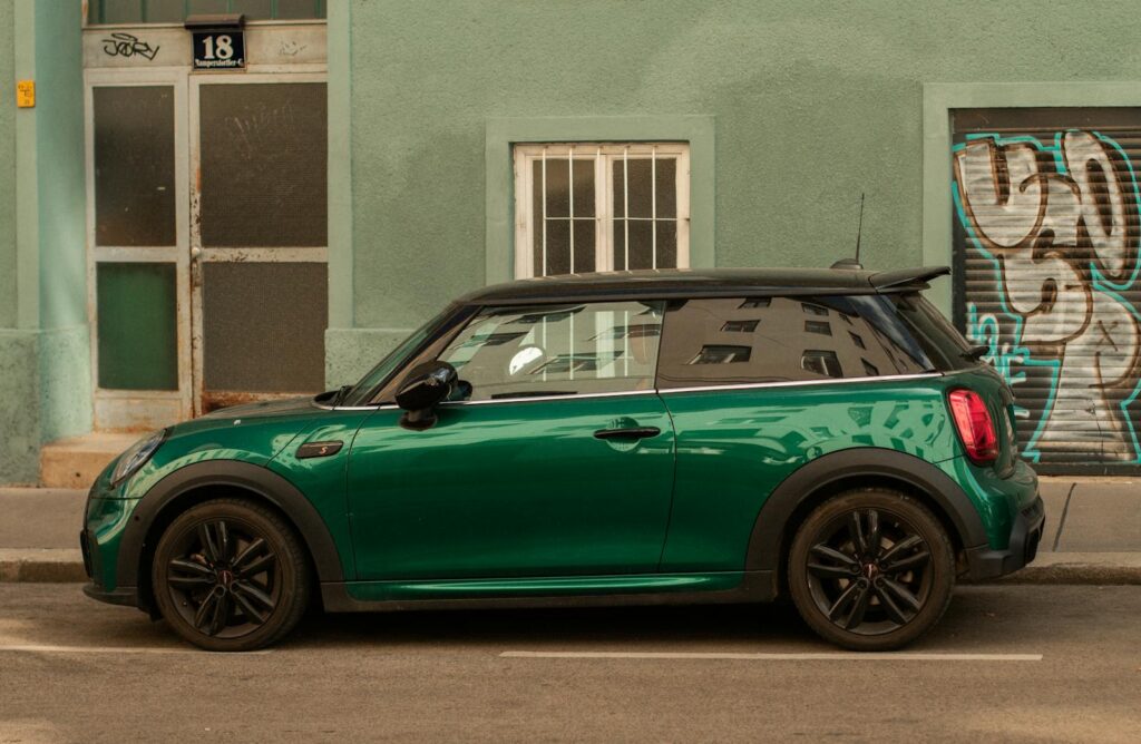 Stunning side profile of a modern green car parked on an urban street with graffiti and colorful architecture.
