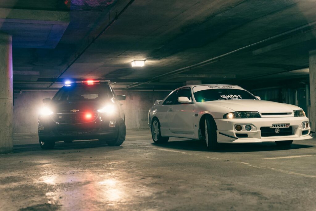 Police and sports cars in a dimly lit underground garage create a tense atmosphere.