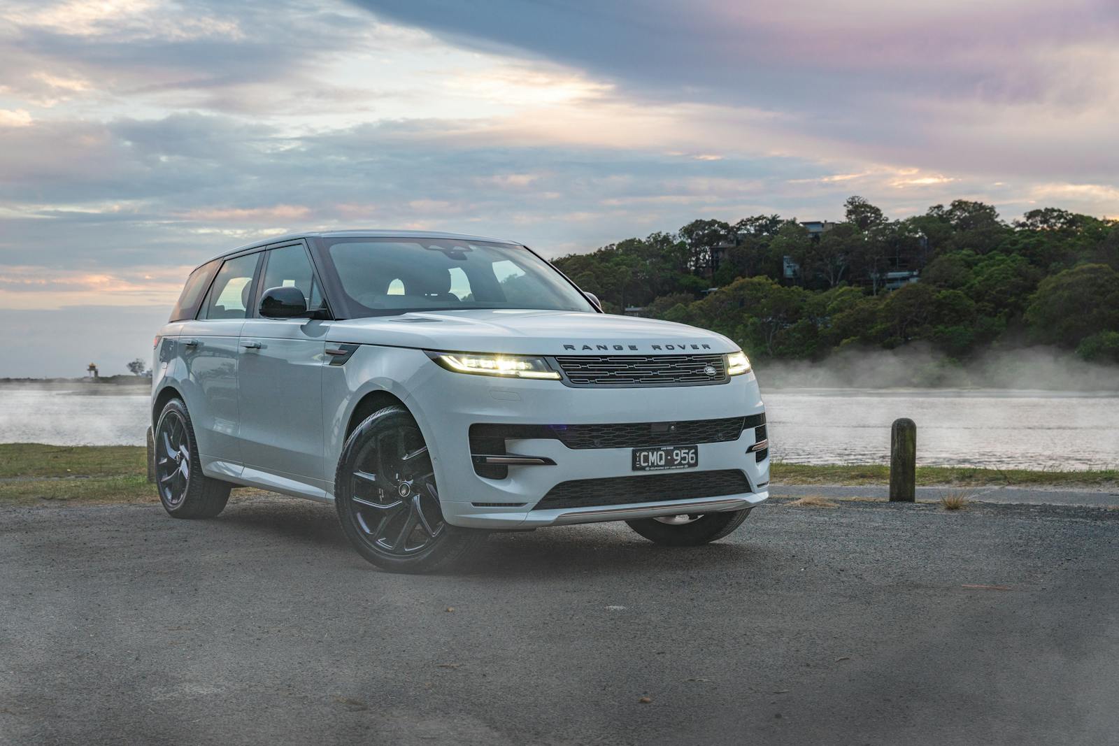 Elegant Range Rover SUV by waterfront during a misty sunrise in Sydney, Australia.