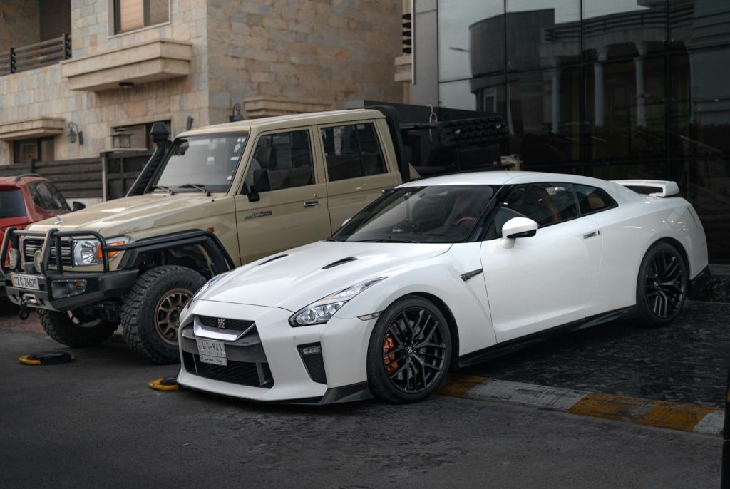 White Nissan GT-R and beige Toyota Land Cruiser parked outdoors in Erbil, Iraq.