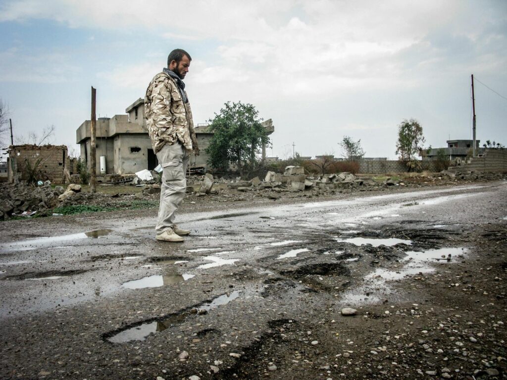 A solitary man walks on a war-ravaged street in Salah ad Din, Iraq amidst destruction.