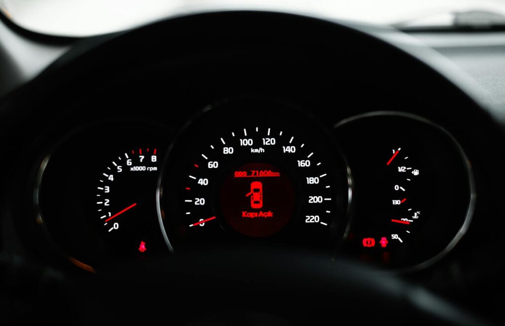 Car dashboard showing a warning light with various dials and gauges in focus.
