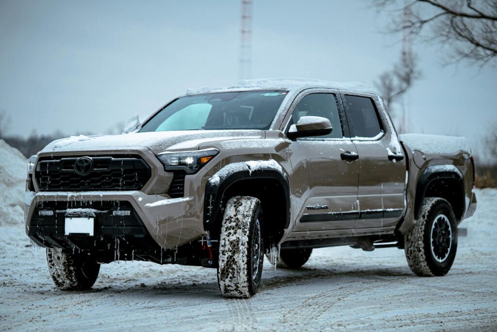Brown pickup truck covered in snow parked outdoors in a winter setting