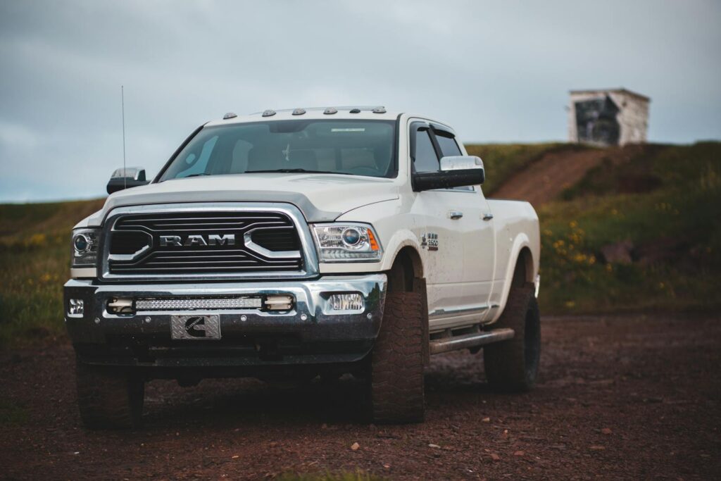 A modern white pickup truck parked on a dirt road in the countryside, showcasing rugged design.
