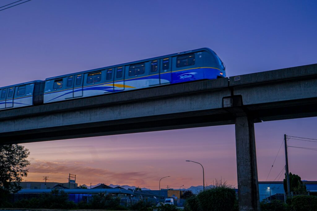 Monorail train travels on elevated track at twilight.
