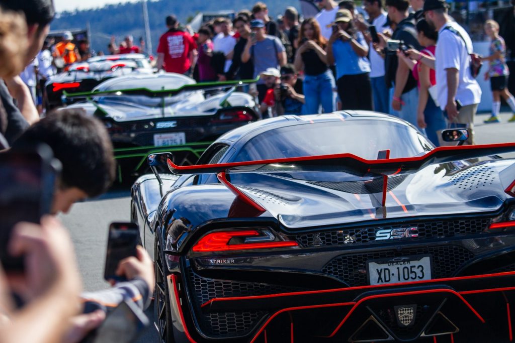Several sleek sports cars lined up with spectators watching
