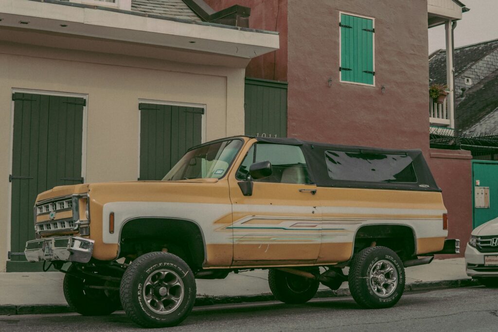 brown and white pickup truck parked beside curb during daytime
