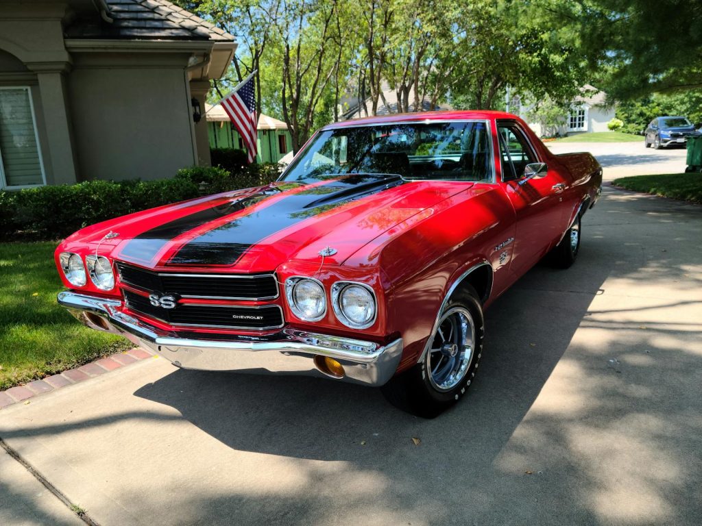 Classic red Chevrolet Chevelle with black stripes parked outdoors on a sunny day.