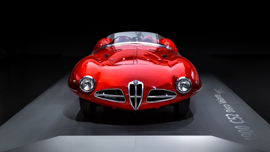 A red car on display in a dark room