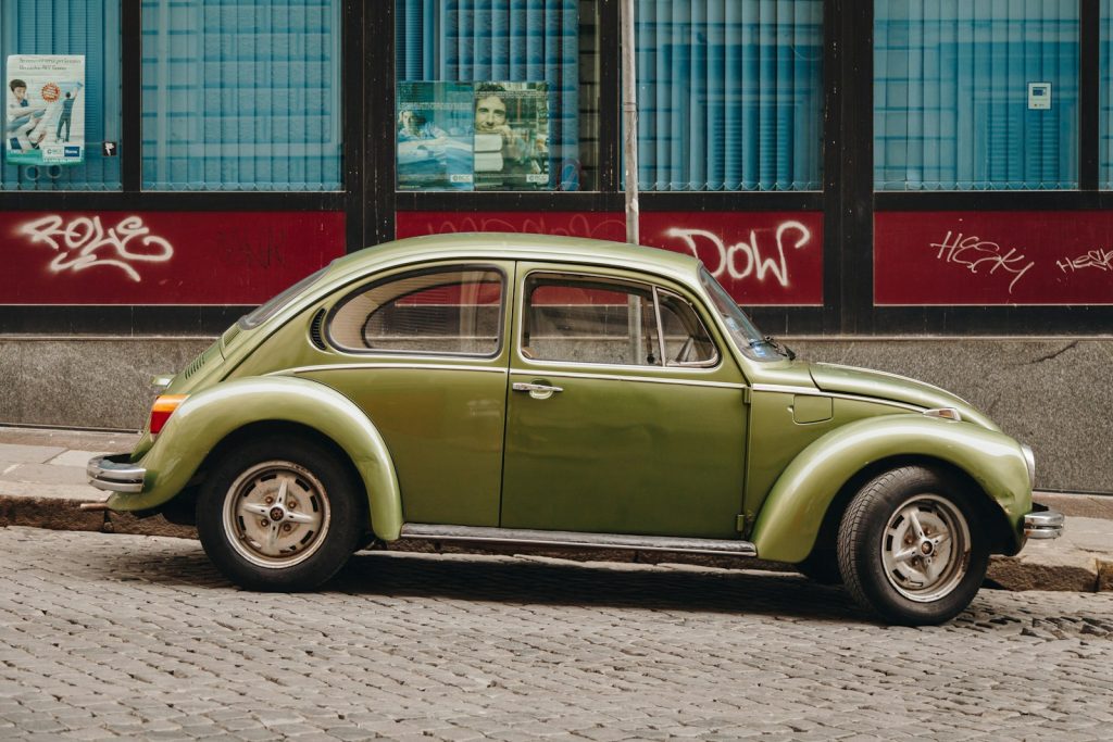 green classic car parked beside red and white building