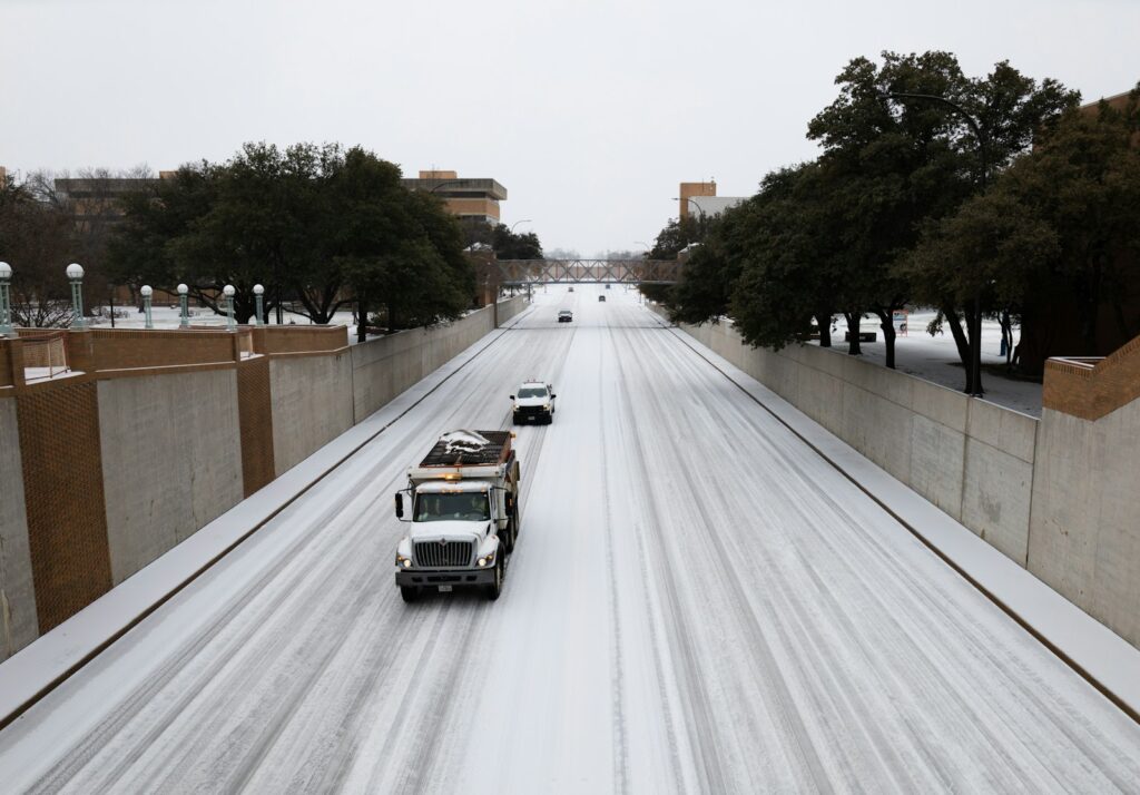 a couple of trucks driving down a snow covered road