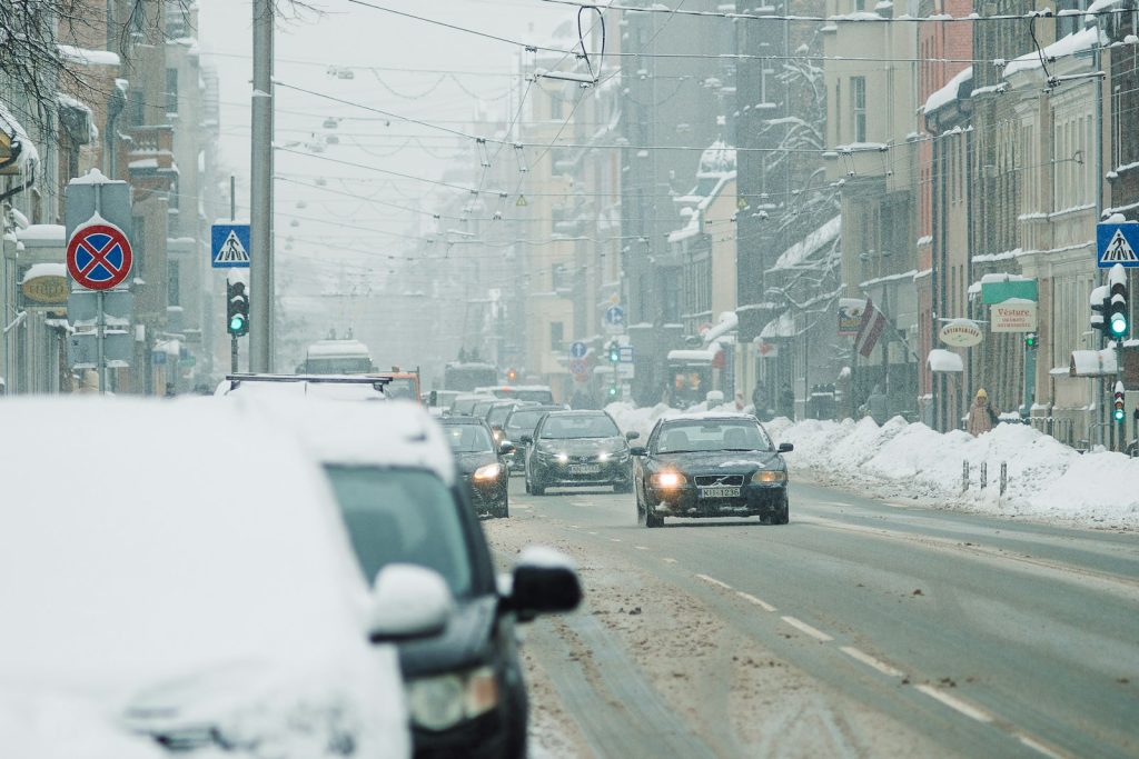cars driving down a snowy street in a city