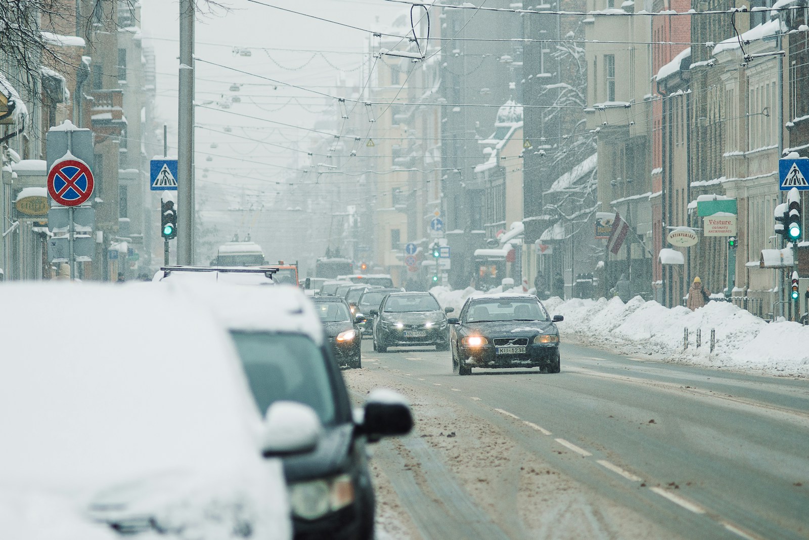 cars driving down a snowy street in a city