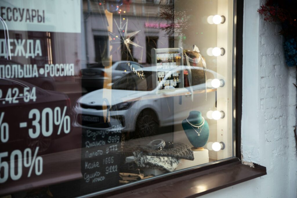A store front window with a car in the reflection