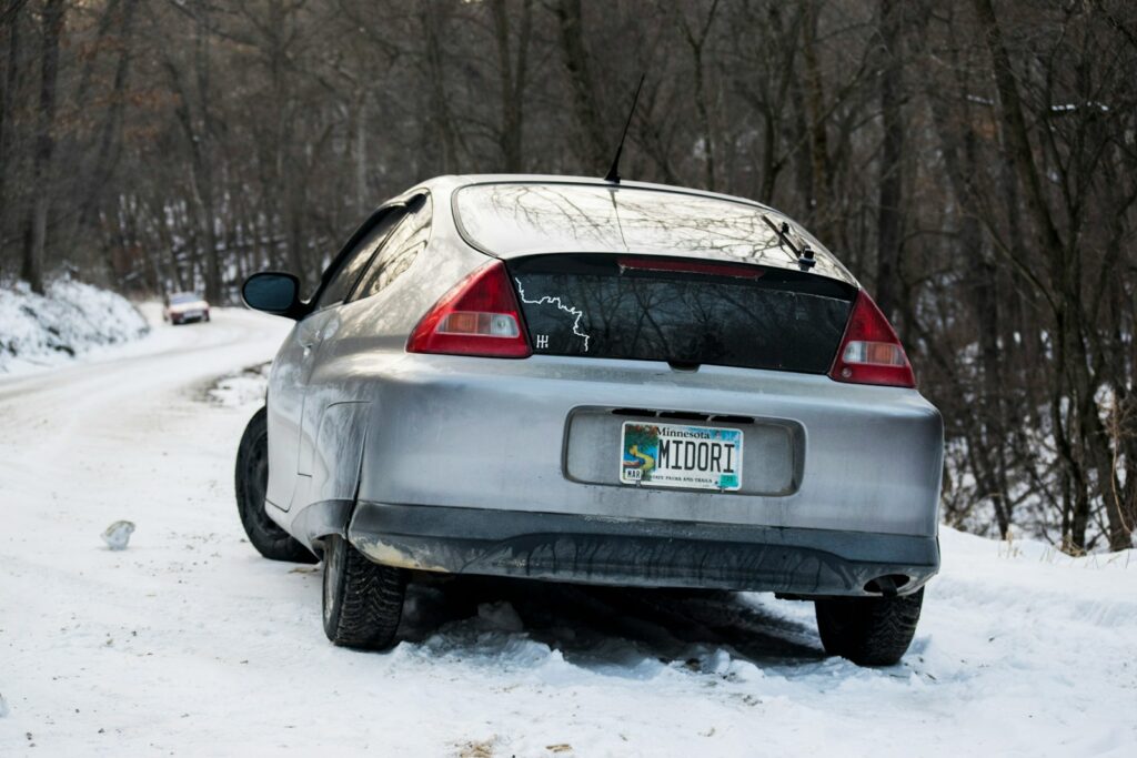 A silver car is driving on a snowy road.
