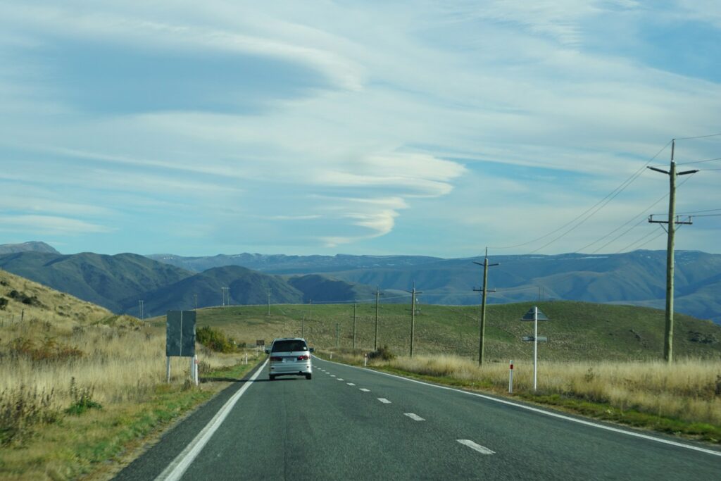 Car driving on a road through rolling hills.