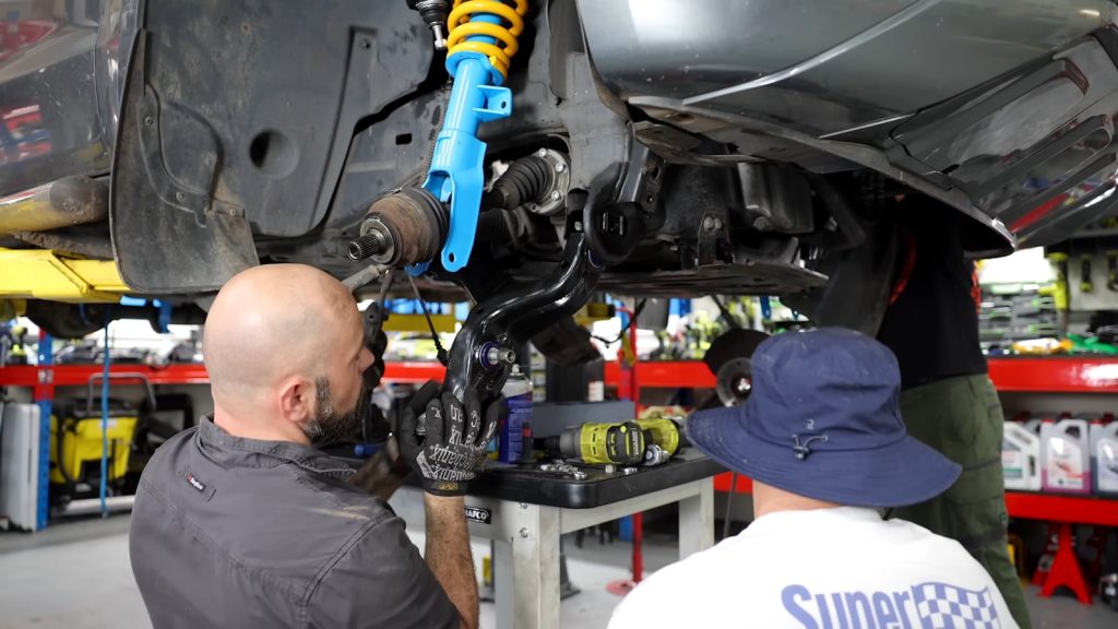 Two men working on a car in a garage