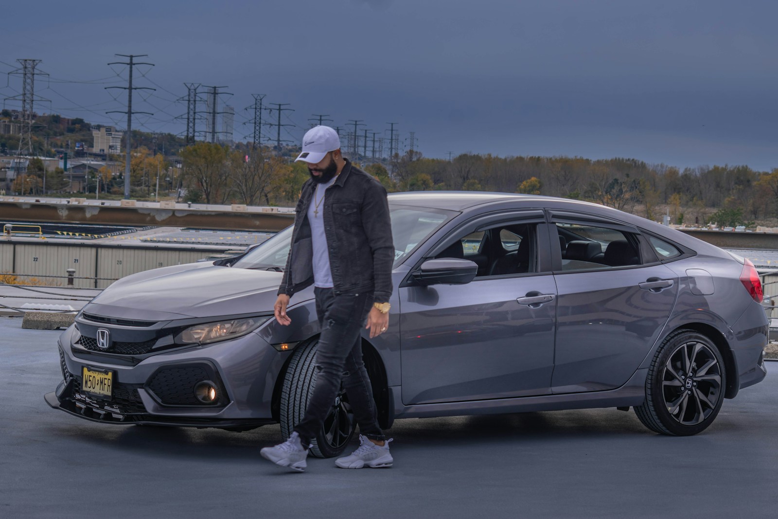 man in black jacket standing beside white car during daytime