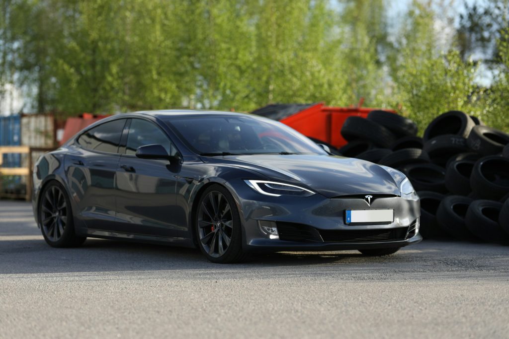 a car parked in a parking lot next to a pile of tires