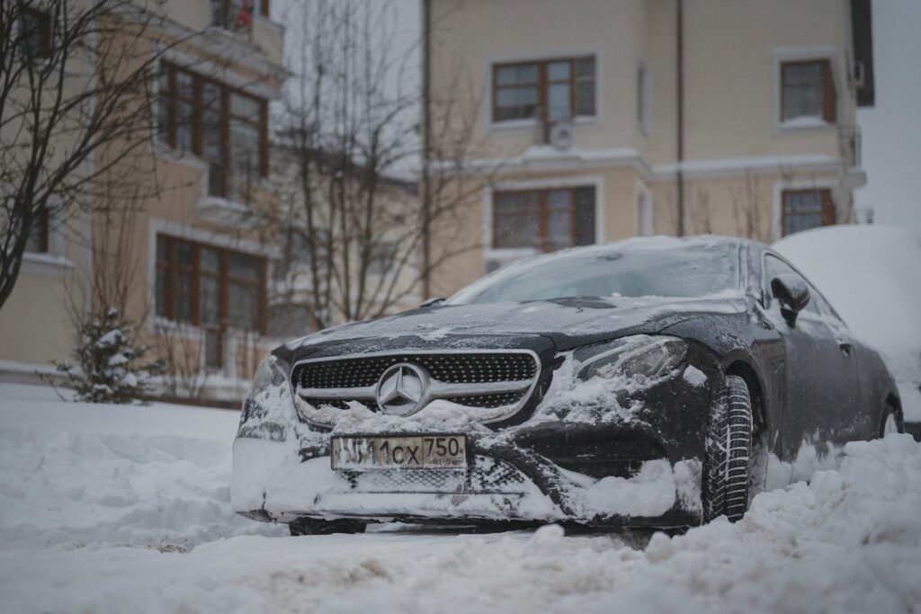 A black car covered in snow on a street.