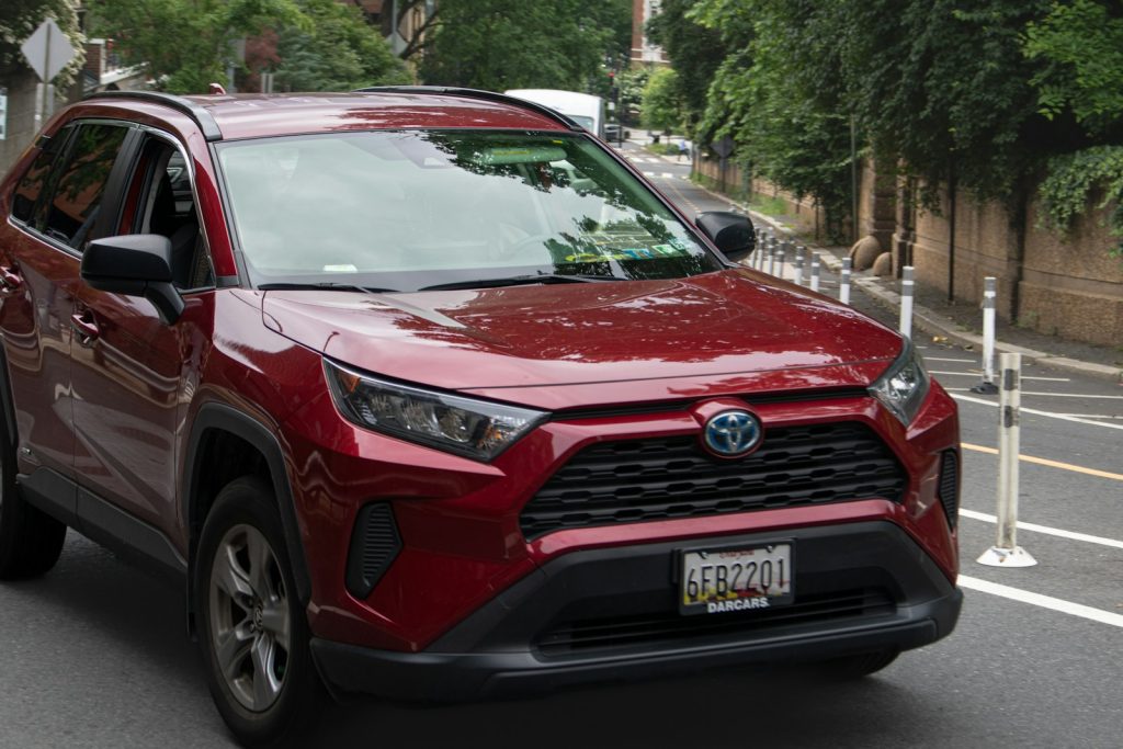 a red toyota rav driving down a street
