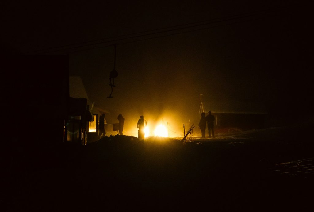 a group of people standing around a fire in the dark