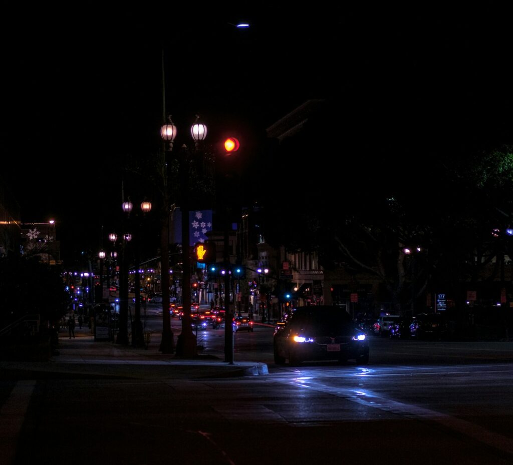Car driving at night on a city street.