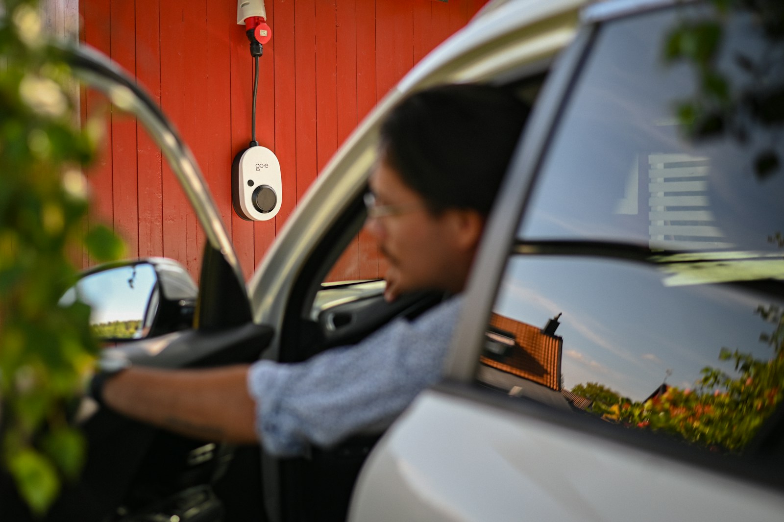 Man entering car near a charging station.