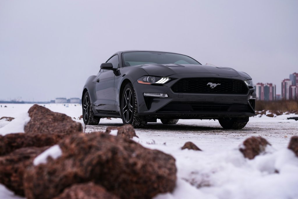 a black mustang parked on a snowy road
