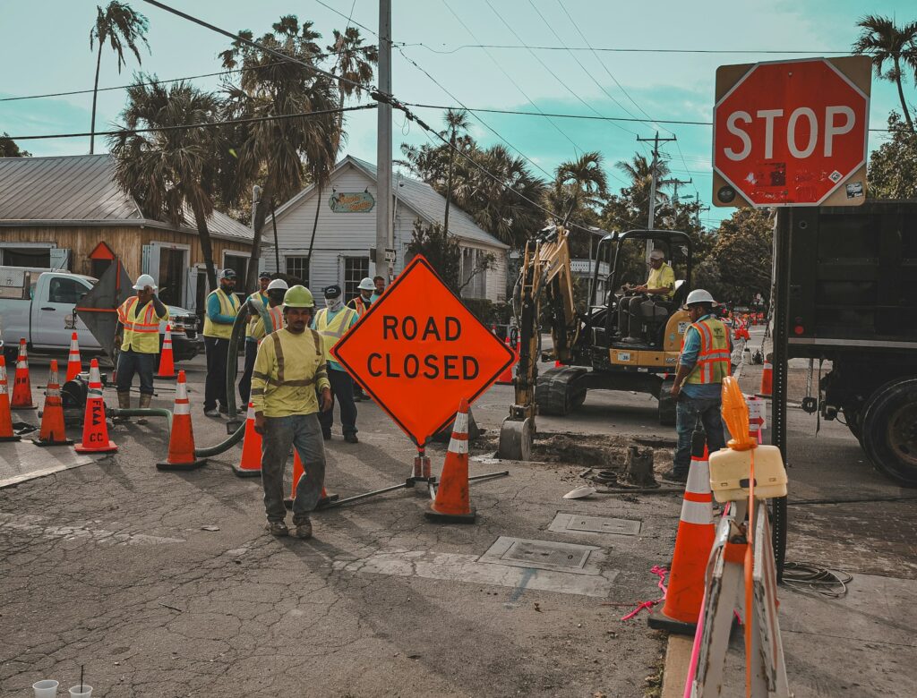 Construction workers and road closed signs on a street.